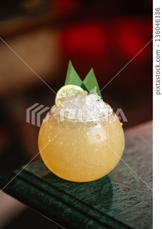 Yellow cocktail in round glass with crushed ice Yellow cocktail in round glass with crushed ice 136046386