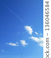 A single contrail and white clouds piercing the blue sky 136046584