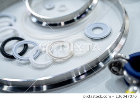 Industrial gasket and sealing rings arranged on stainless steel surface in manufacturing. Precision engineering, material quality, and components used for mechanical assembly and industrial systems. 136047070