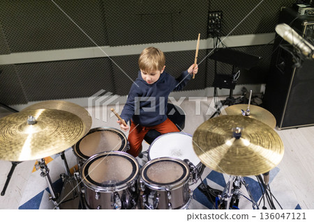 Young boy practicing drums, developing musical talent 136047121