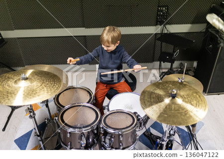 Little boy enjoying playing drum set in music studio Little boy enjoying playing drum set in music studio 136047122