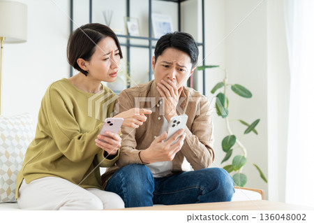 A middle-aged couple using smartphones in the living room A middle-aged couple using smartphones in the living room 136048002