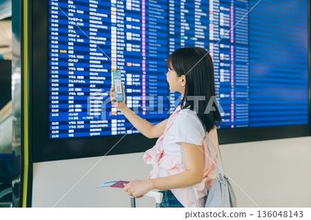 A woman checking the electronic display board at the airport (Photo courtesy of Kansai International Airport (KIX)) A woman checking the electronic display board at the airport (Photo courtesy of Kansai International Airport (KIX)) 136048143