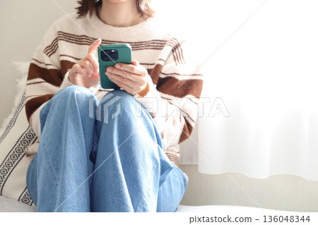 A woman operating a smartphone 136048344