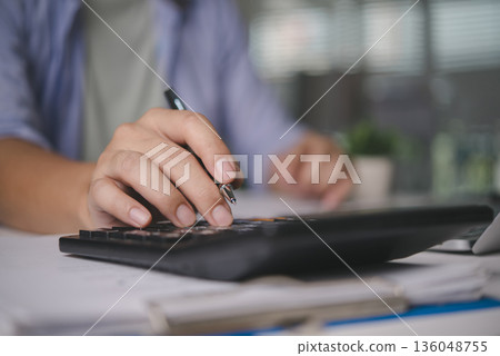 Accountant calculating finance data on calculator, working on business documents, audit report, money management, tax season, investment analysis, financial planning with paperwork at the office. Accountant calculating finance data on calculator, working on business documents, audit report, money management, tax season, investment analysis, financial planning with paperwork at the office. 136048755