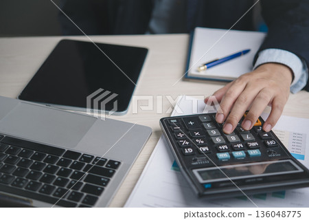 Accountant works with calculator near spreadsheet and notebook in workspace for invoice billing tax preparation audit financial statement accuracy efficiency concept. 136048775