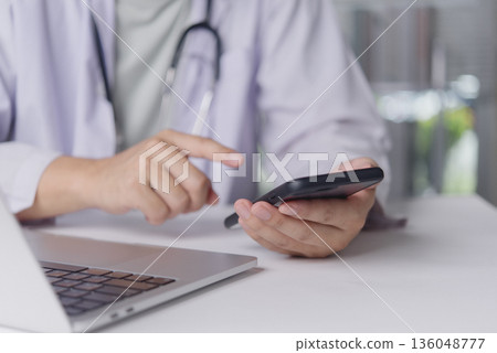 Healthcare professional checks mobile phone in office for appointment alert email consultation telehealth coordination digital record management productivity efficiency concept. Healthcare professional checks mobile phone in office for appointment alert email consultation telehealth coordination digital record management productivity efficiency concept. 136048777