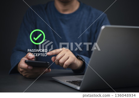 Security, Password Hands holding smartphone show password accepted next to laptop in home office to complete login, illustrating strong 2FA, OTP, and data protection concept. 136048934