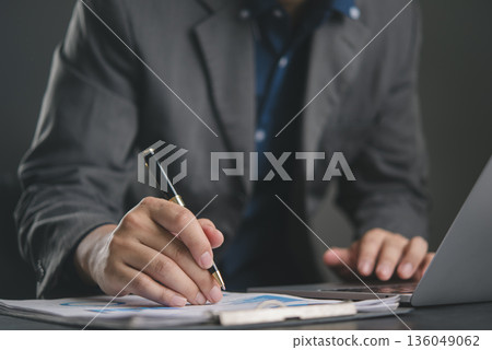 Data analysis. Business professional signs report with pen while using laptop at desk, organizing office workflow with chart, graph, numbers, and planning. concept finance Data analysis. Business professional signs report with pen while using laptop at desk, organizing office workflow with chart, graph, numbers, and planning. concept finance 136049062