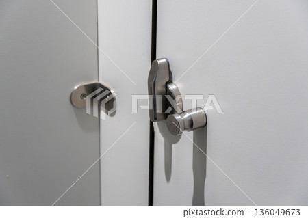 A stylish cabinet door latch catches the light, showcasing its modern design in a bright, contemporary room filled with tranquility 136049673