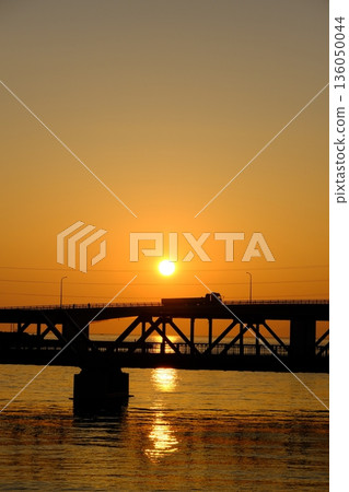 A truck crossing a bridge illuminated by the setting sun A truck crossing a bridge illuminated by the setting sun 136050044