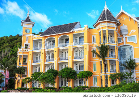 A yellow building with a clock tower and a balcony 136050119
