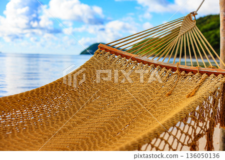 A beach scene with a large yellow hammock hanging over the water A beach scene with a large yellow hammock hanging over the water 136050136