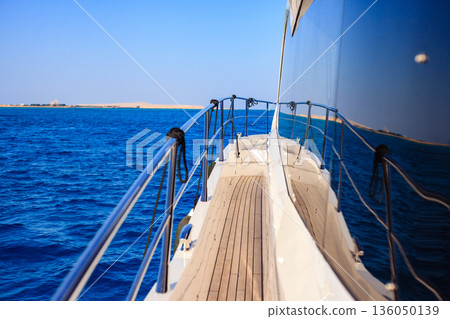 A boat is sailing in the ocean with a blue sky in the background 136050139