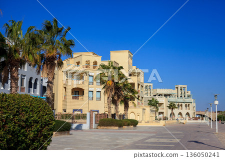El Gouna Egypt 2.11.2025. A street with a row of buildings and palm trees El Gouna Egypt 2.11.2025. A street with a row of buildings and palm trees 136050241