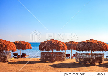 A beach with several umbrellas and chairs A beach with several umbrellas and chairs 136050271