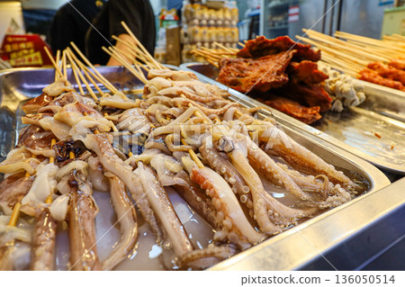 A tray of octopus is displayed with skewers A tray of octopus is displayed with skewers 136050514