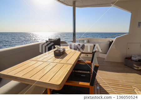 A wooden table with a chair and a towel on it is on a boat 136050524