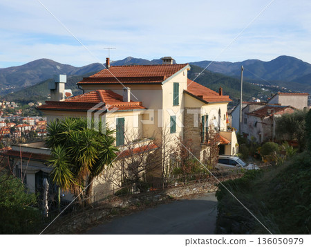 Traditional buildings, mountain houses. Nature and architecture of Liguria. Blue sky, clouds, and backdrop for design. 136050979