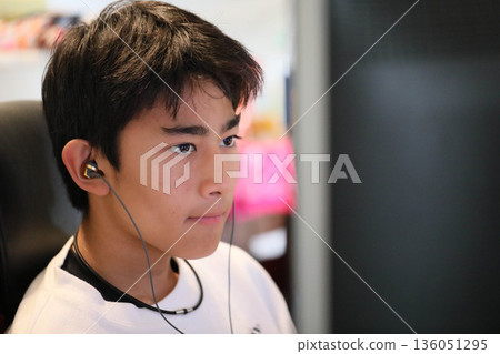 一名學生戴著耳機使用電腦。 一名學生戴著耳機使用電腦。 136051295