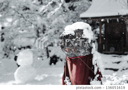 冬日景象，一座被雪覆蓋的石像和一條紅色圍裙 136051619