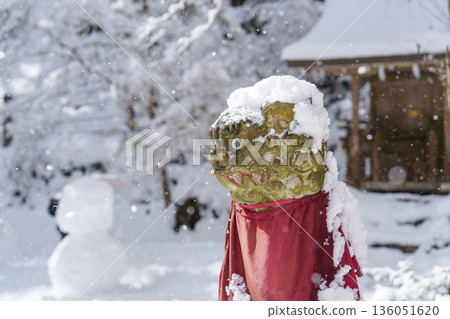 冬日景象，一座被雪覆蓋的石像和一條紅色圍裙 136051620