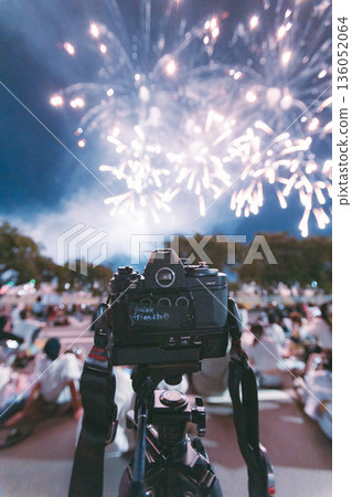 Fireworks in the night sky and a camera on a tripod 136052064