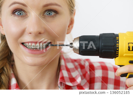 Woman with braces using drill on her teeth 136052185