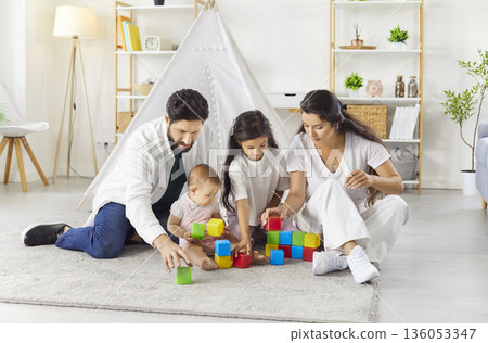Parents and children playing with colorful building blocks together in cozy living room Parents and children playing with colorful building blocks together in cozy living room 136053347