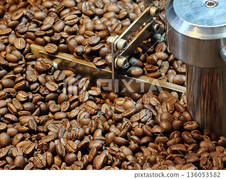Freshly roasted coffee beans are being processed, showcasing their rich brown color and texture. image captures essence of coffee production, evoking sense of warmth and aroma Freshly roasted coffee beans are being processed, showcasing their rich brown color and texture. image captures essence of coffee production, evoking sense of warmth and aroma 136053582