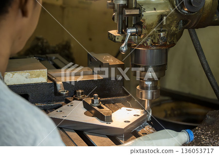 Machine Operator Performing Plunge Rough Cutting on Metal Plate with Flat End Mill in NC Milling Machine 136053717