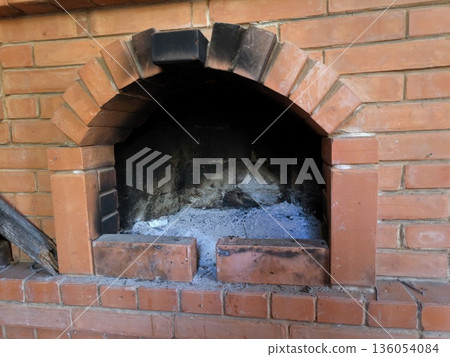 stone fired outdoor pizza oven with two pizzas ready to cook. Brick red oven 136054084