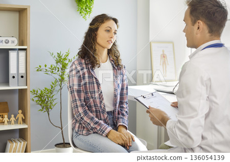 Female patient with doctor during stethoscope chest exam in bright clinic Female patient with doctor during stethoscope chest exam in bright clinic 136054139