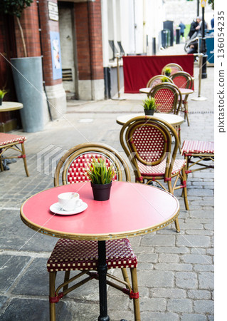 Red round tables and mesh chairs lined up in front of a restaurant in Windsor, a suburb of London 136054235