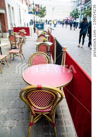 在倫敦郊區溫莎的一家餐廳前,擺放著一排紅色圓桌和網狀椅。 在倫敦郊區溫莎的一家餐廳前,擺放著一排紅色圓桌和網狀椅。 136054236