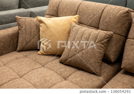 Cozy brown fabric sofa with beige and brown cushions in living room 136054291