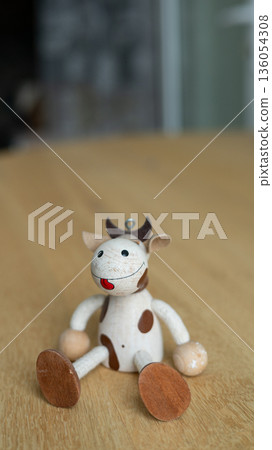 Wooden cow toy with red smile on wooden table Wooden cow toy with red smile on wooden table 136054308