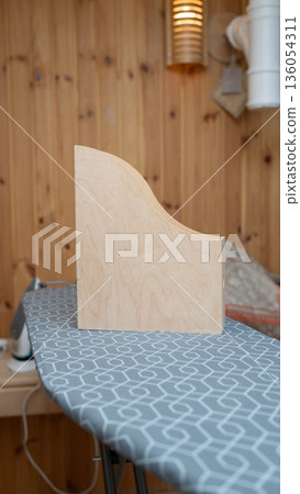 Wooden bookend on geometric patterned ironing board in cozy room 136054311
