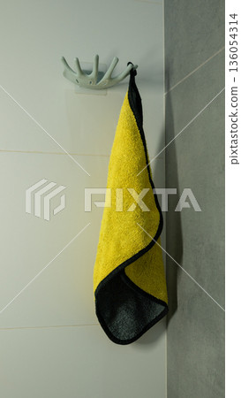 Yellow towel hanging on antler hook in modern bathroom setting Yellow towel hanging on antler hook in modern bathroom setting 136054314