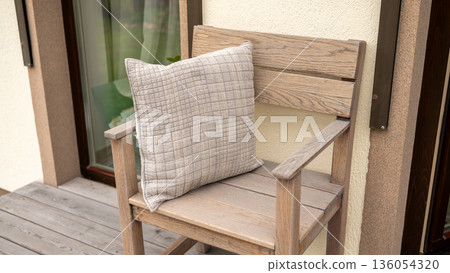 Wooden chair with checkered cushion on rustic porch 136054320