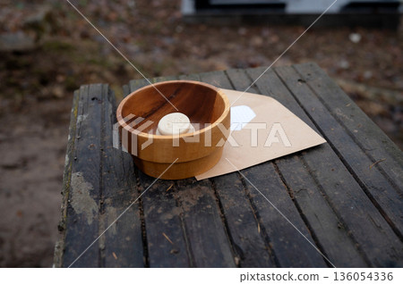 Rustic wooden bowl with carved ball on weathered table outdoors 136054336
