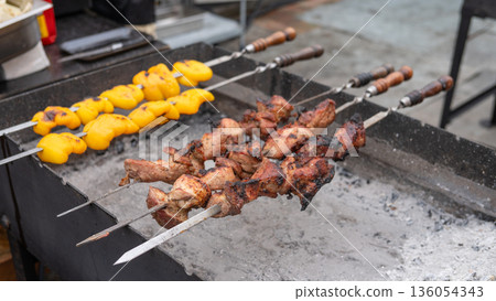 Grilled meat and vegetables on skewers cooking over charcoal Grilled meat and vegetables on skewers cooking over charcoal 136054343