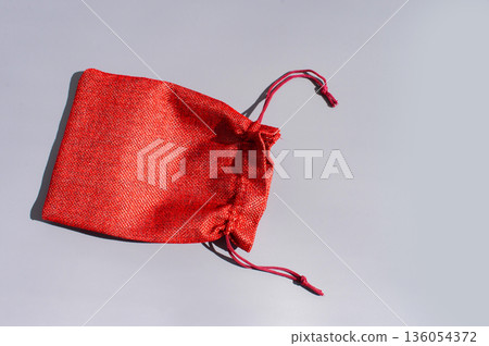 Red fabric drawstring bag on gray background with shadows 136054372