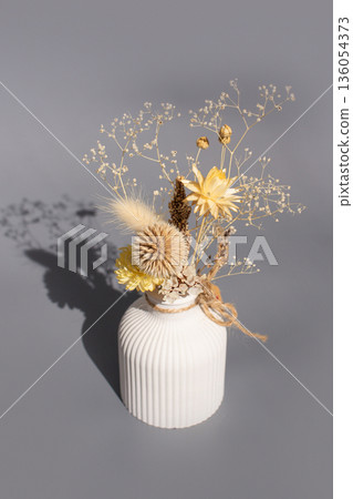 Elegant floral arrangement in white vase with dried flowers and delicate blossoms 136054373
