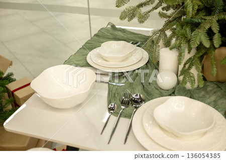 Elegant table setting with white dishes and greenery Elegant table setting with white dishes and greenery 136054385