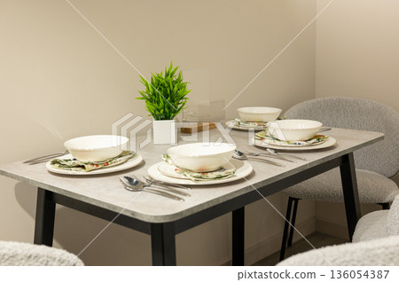 Elegant dining table setup with white tableware and green plant 136054387