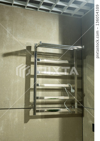 Wall-mounted stainless steel heated towel rack in modern bathroom Wall-mounted stainless steel heated towel rack in modern bathroom 136054389