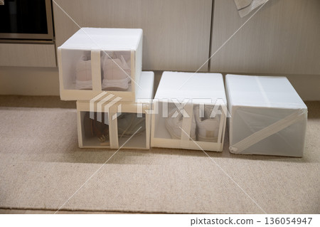 Minimal home organization concept with white fabric shoe storage boxes neatly stacked on floor Minimal home organization concept with white fabric shoe storage boxes neatly stacked on floor 136054947