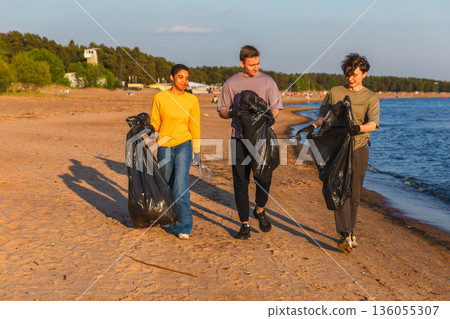 Earth day. Volunteers activists team collects garbage cleaning of beach coastal zone. Woman mans with trash in garbage bag on ocean shore. Environmental conservation coastal zone cleaning Earth day. Volunteers activists team collects garbage cleaning of beach coastal zone. Woman mans with trash in garbage bag on ocean shore. Environmental conservation coastal zone cleaning 136055307