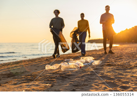 Earth day. Volunteers activists team collects garbage cleaning of beach coastal zone. Woman mans with trash in garbage bag on ocean shore. Environmental conservation coastal zone cleaning Earth day. Volunteers activists team collects garbage cleaning of beach coastal zone. Woman mans with trash in garbage bag on ocean shore. Environmental conservation coastal zone cleaning 136055314
